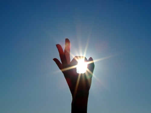 silhouette-of-a-female-hand-the-blue-sky-and-the-bright-sun